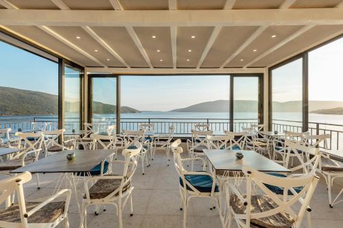 un restaurante con mesas y sillas y vistas al agua en SkyView apartments, en Herceg-Novi