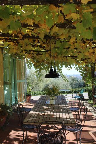 um pátio com uma mesa e cadeiras sob uma pérgola em Azienda Agricola Fabbrica Di San Martino em Lucca