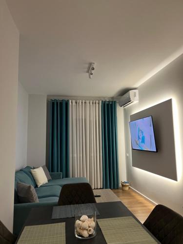 uma sala de estar com um sofá e uma televisão de ecrã plano em Jur Apartment em Durrës