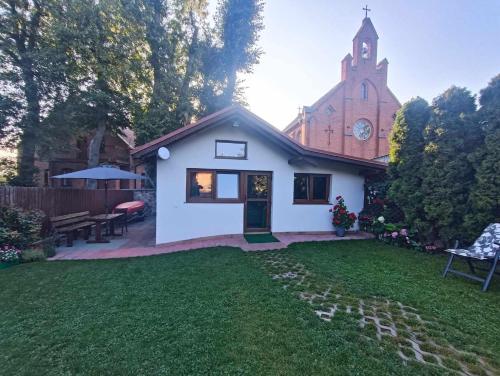 uma pequena casa branca com uma igreja com uma torre de relógio em Domek z kominkiem, Ukta 63, Mazury, em Ruciane-Nida