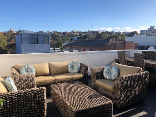 a patio with chairs and couches on a roof at XQ Collection La Casa De Frida - Modern Studio with Balcony in Sydney