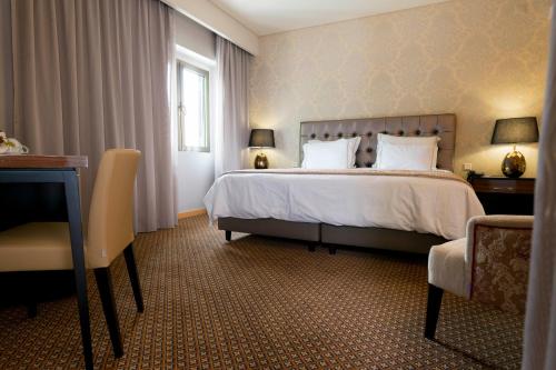 a hotel room with a bed and a desk at Hotel Lis Batalha in Batalha