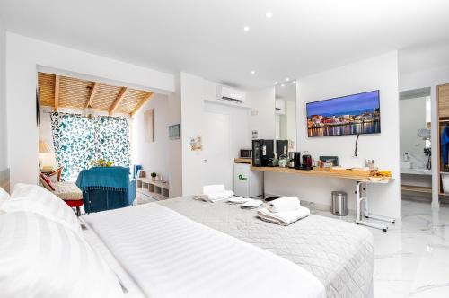 a white bedroom with a large white bed and a tv at Notus Chania Crete in Chania Town