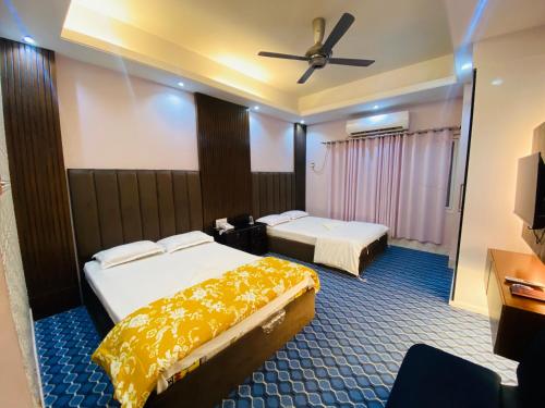 a hotel room with two beds and a ceiling fan at Hotel Grand Akther in Sylhet