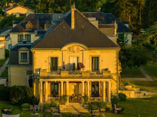 una grande casa bianca con portico e balcone di Garrigae Manoir de Beauvoir Poitiers Sud - Hotel & Spa a Mignaloux-Beauvoir