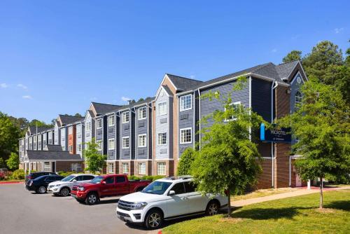 Microtel Inn by Wyndham Raleigh-Durham Airport في موريسفيل: مبنى كبير به سيارات تقف في موقف للسيارات