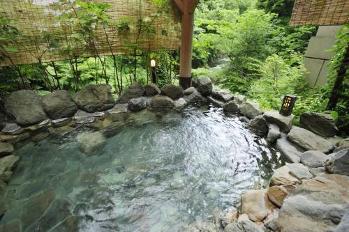 uma piscina de água com pedras num quintal em Koorogirou em Kaga