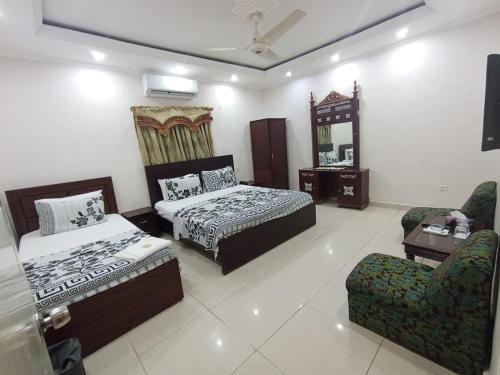 um quarto com 2 camas, uma cadeira e um espelho em Hotel Royal Residency em Karachi