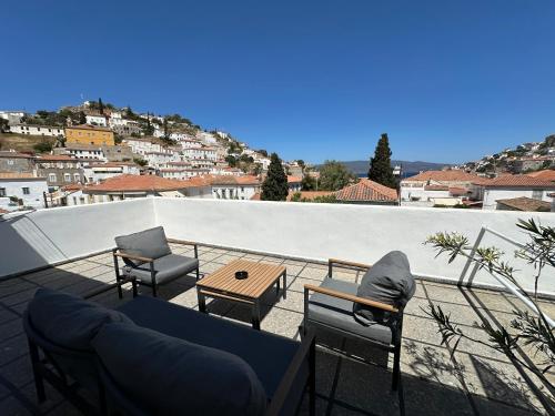 uma varanda com um sofá, cadeiras e uma mesa em Hotel Miranda em Hydra