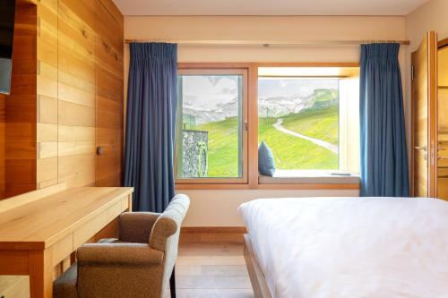 een slaapkamer met een bed, een bureau en een raam bij chetzeron in Crans-Montana