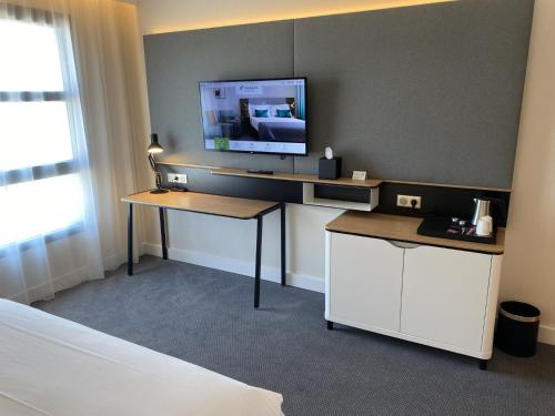 una camera con scrivania e televisore di Holiday Inn Dijon Sud - Longvic, an IHG Hotel a Digione