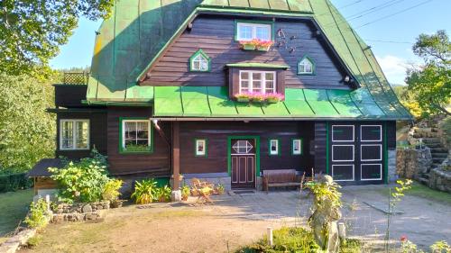 uma casa de madeira com um telhado verde e um quintal em Prawdzicówka em Zachełmie