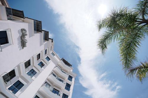 ein hohes weißes Gebäude mit einer Palme daneben. in der Unterkunft Sea View Hotel in Himarë