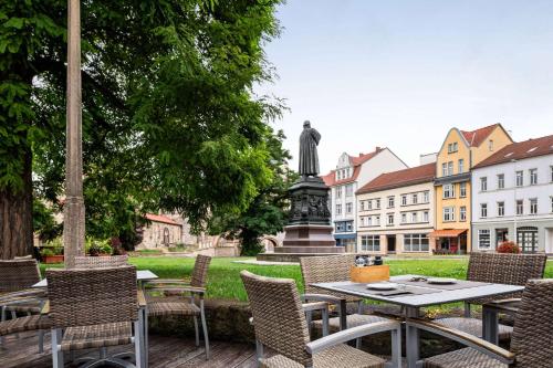 una mesa y sillas con una estatua en el fondo en Vienna House by Wyndham Thüringer Hof Eisenach, en Eisenach