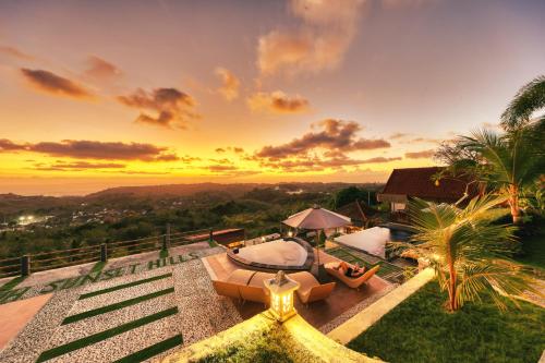 um pôr-do-sol sobre uma villa com vista para o oceano em Sebuluh Sunset Hill em Nusa Penida