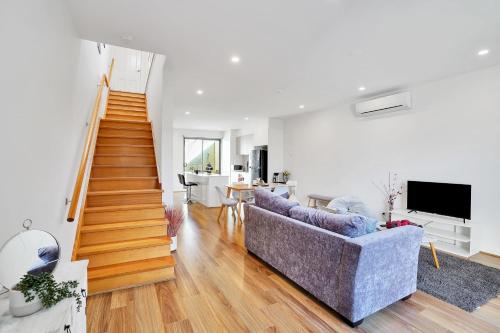 a living room with a couch and a staircase at Cozy Townhouse in Werribee centre in Werribee