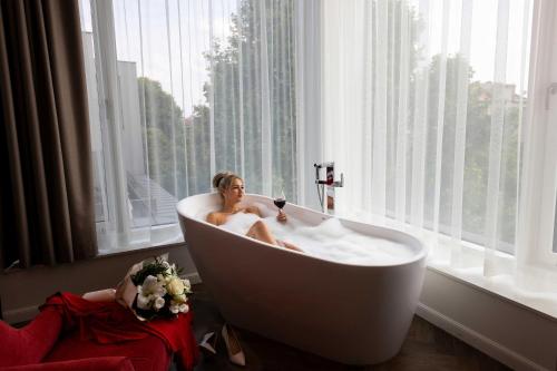 une femme assise dans une baignoire dans une fenêtre dans l'établissement Three Corners Avenue Hotel, à Budapest