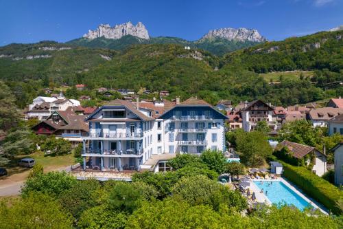 a resort with a pool and mountains in the background at Hotel du Lac in Talloires