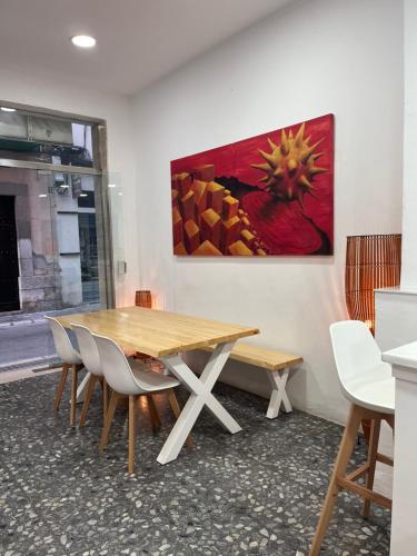 una mesa de madera con sillas y una pintura en la pared en Hotel Ibiza, en Sitges