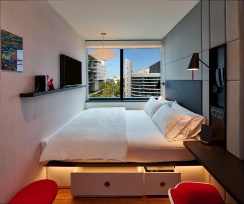 een slaapkamer met een groot bed en een raam bij citizenM Miami South Beach in Miami Beach