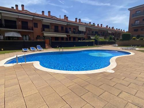 una grande piscina con due sedie e un edificio di Apartamento Loft, LLoret de Mar a Lloret de Mar