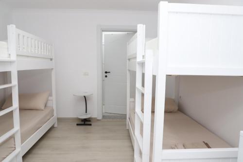 um quarto com beliches brancos e uma secretária em Aral Hostel em Berati