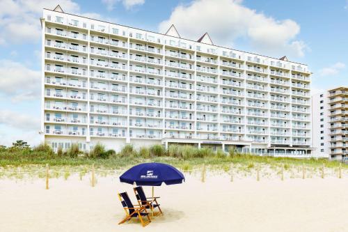 um hotel na praia com duas cadeiras e um guarda-sol em Hilton Garden Inn Ocean City Oceanfront em Ocean City