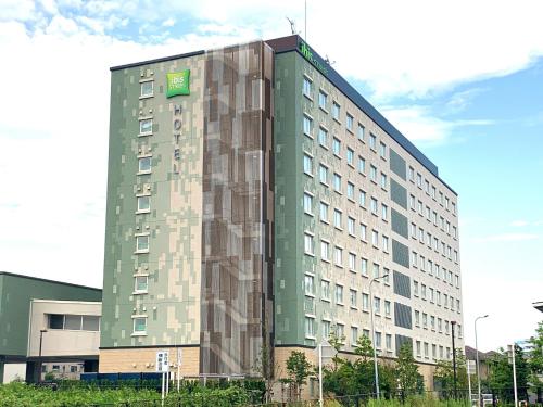 ein hohes, grünes Gebäude mit einem grünen Schild drauf in der Unterkunft ibis Styles Tokyo Bay in Urayasu