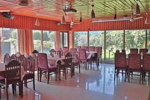 uma sala de jantar com mesas, cadeiras e janelas em Hotel kabir em Srinagar