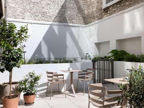 un patio avec des tables, des chaises et des plantes dans l'établissement Hotel Maison Hamelin Paris - Handwritten Collection, à Paris