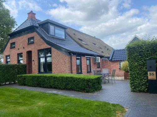 una casa de ladrillo rojo con techo negro en Kindvriendelijk appartement de Hooge Stukken onder de rook van Groningen, en Eelde-Paterswolde