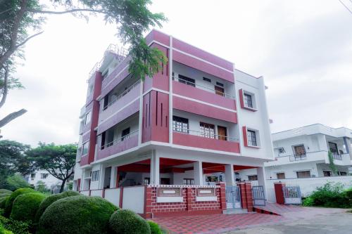 um edifício vermelho e branco com árvores em frente em Coorg Residency home stay em Kushālnagar