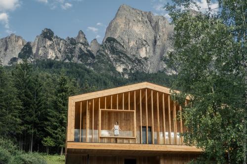 una pequeña casa de madera frente a una montaña en Dolmites Nature Hotel Vigilerhof, en Siusi