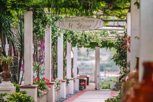 een loopbrug in de tuin met een bord dat de achtertuin paarlen zomer leest bij Hotel Giordano in Ravello