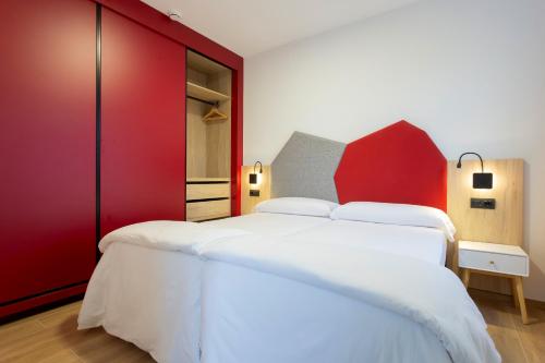 1 dormitorio con 1 cama blanca grande y paredes rojas en Sholeo Lodges Las Palmas Flats, en Las Palmas de Gran Canaria