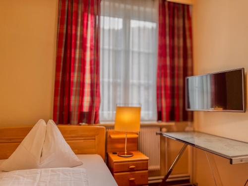 - une chambre avec un lit et un bureau avec une télévision dans l'établissement STIERSCHNEIDER'S Weinhotel Wachau & Wiazhaus, à Spitz