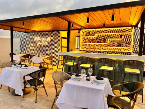 a restaurant with two tables and chairs and a bar at Areia Boutique Hotel - Puerto Morelos in Puerto Morelos