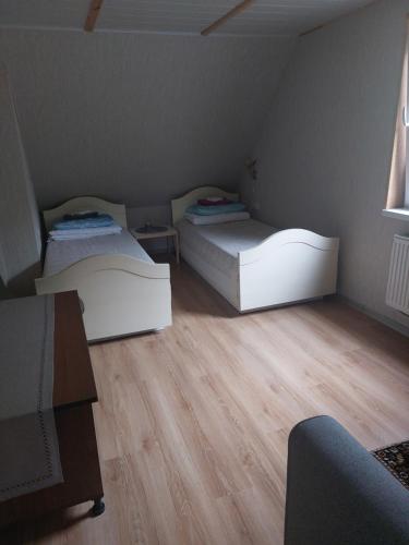 twee bedden in een kleine kamer met houten vloeren bij Dariaus ir Gireno 7 in Zarasai