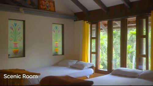 two beds in a room with windows and a room at Saaranga homestay in Avathi