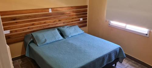 um quarto com uma cama azul e uma cabeceira em madeira em Dtos El Descanso em Termas de Río Hondo