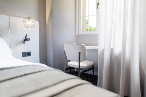 a bedroom with a chair and a bed and a window at Schwarzer Adler - Concept Living in Vipiteno