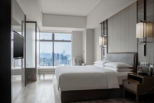 una camera da letto con un grande letto bianco e una grande finestra di Chongqing Marriott Hotel a Chongqing