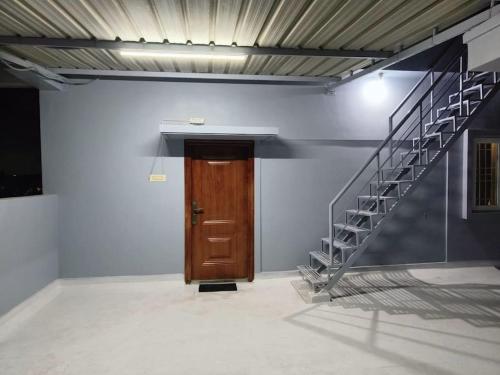 a hallway with a wooden door and a staircase at V4 Stay - Luxury 1 BHK AC Suite sleeps 5 guests in Coimbatore