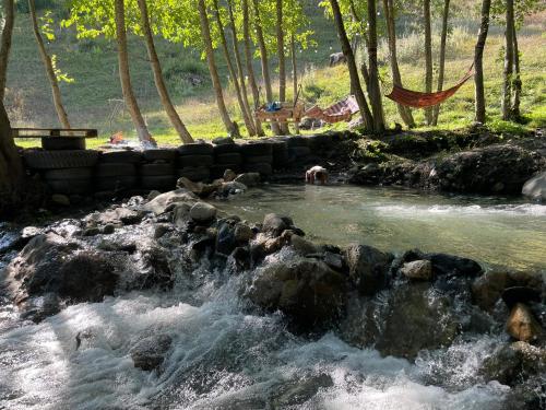 a river with rocks and people swimming in it at River side SVANETI in Mestia