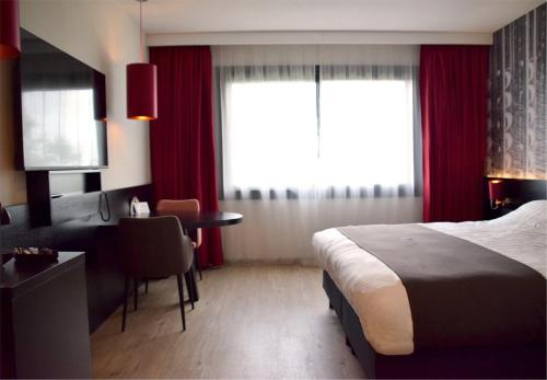 Pokój hotelowy z łóżkiem, biurkiem i stołem w obiekcie Bastion Hotel Tilburg w mieście Tilburg