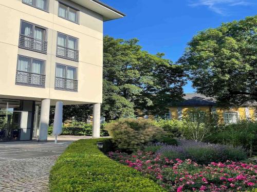 un bâtiment avec un jardin en face dans l'établissement Mercure Hotel Gera City, à Gera