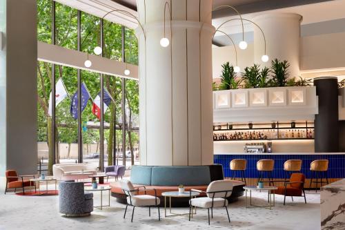 una hall con tavoli, sedie e finestre di Paris Marriott Rive Gauche Hotel & Conference Center a Parigi