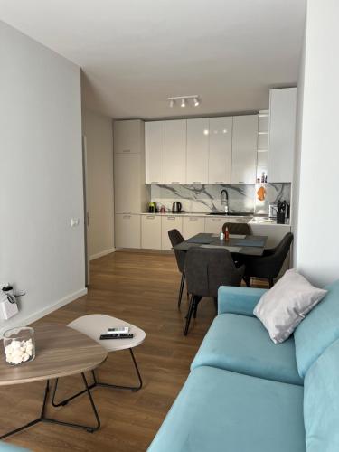 uma sala de estar com um sofá azul e uma cozinha em Jur Apartment em Durrës