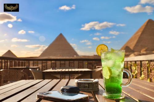 una bebida en una mesa con vistas a las pirámides en Comfort Sphinx&Pyramids Inn en El Cairo