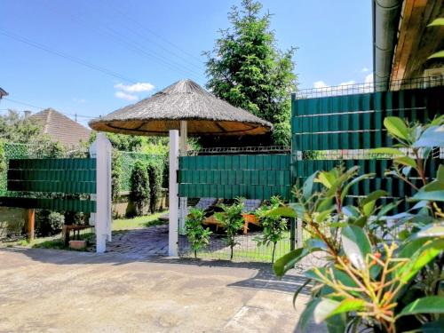 an umbrella in a garden with a fence at Apartman TESLA 29 in Veternik